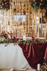 Banquet white table, presidium, candles, composition of flowers of pink, white, rose, hydrangea. Candles, crystal, garlands. Decor wine and marsala colors