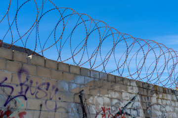 Gray brick wall with graffiti and barbed wire