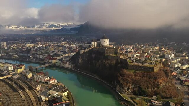 Aerial view of mountain town Kufstein with medieval hilltop fortress, dramatic winter scenery at sunrise, river Inn meandering through the valley - Austrian Alps from above, Tyrol, Austria, Europe