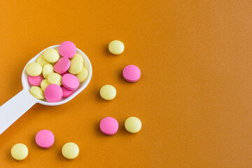 Colored pills on the table. Medical preparations on an orange background. Place for text.