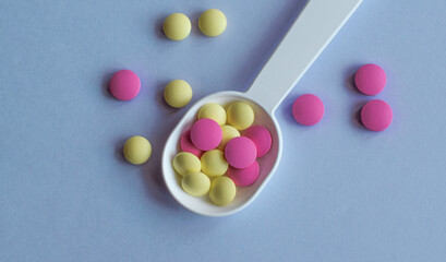 Colored pills on the table. Medical drugs on a blue background. Place for text.