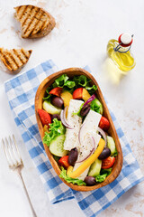 Greek salad in wooden plate on a white background. Traditional Greek dish. Selective focus. Top view.