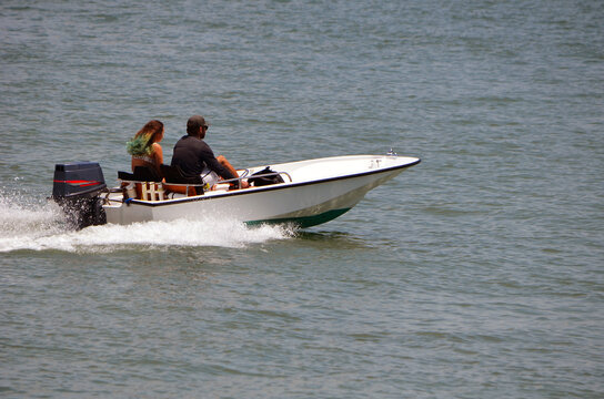 Young couple enjoying a fast cruise on Biscayne Bay off Miami Beach,Florida in a small white fishing skiff
