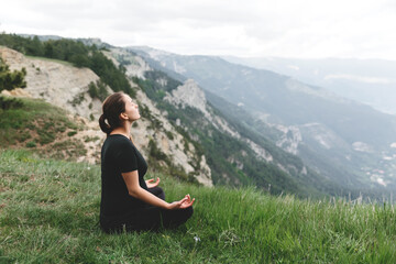 Naklejka na ściany i meble pregnant girl doing yoga or meditating, in the mountains, in the park or outdoors in the afternoon