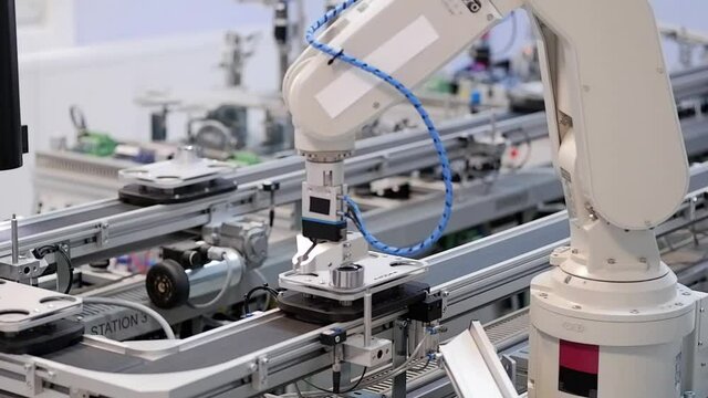 Close-up of robot arm pick product from automated car and place to station to be assembly. Industry 4.0 smart factory concept; robot arm assembles the product. Selective focus.