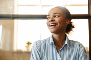 Photo of joyful african american woman smiling while leaning on wall