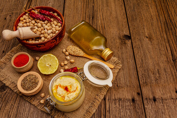 Hummus on old wooden boards background. Dry chickpea, olive oil, lemon, cumin and chili pepper