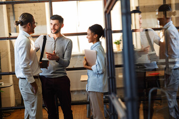 Photo of multinational pleased colleagues talking and smiling