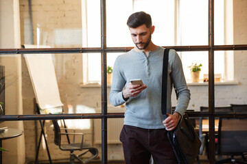 Photo of focused caucasian man using cellphone while standing