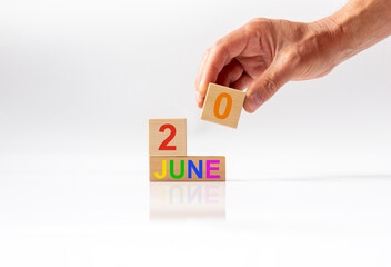 june 20th. Day 20 of month,hand holda cube of wooden calendar on white glossy background....