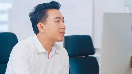 Fototapeta premium Successful executive Asian young businessman smart casual wear using desktop computer thinking of inspiration search problem solution ideas lost during working process in modern office workplace.