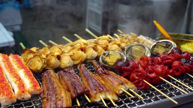 Close up of grilled seafood on roaster with smoke, Japanese street food concept