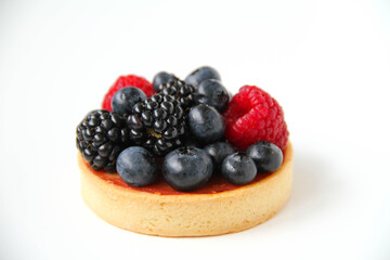 French dessert. Berry tart decorated with organic fresh blueberries, raspberries and blackberries. White background. Back view. 