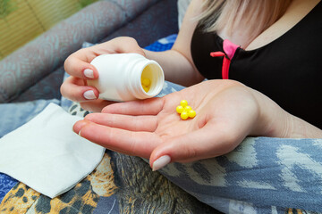 the girl holds a handful of yellow tablets in the palm of her hand to treat a dangerous disease,...