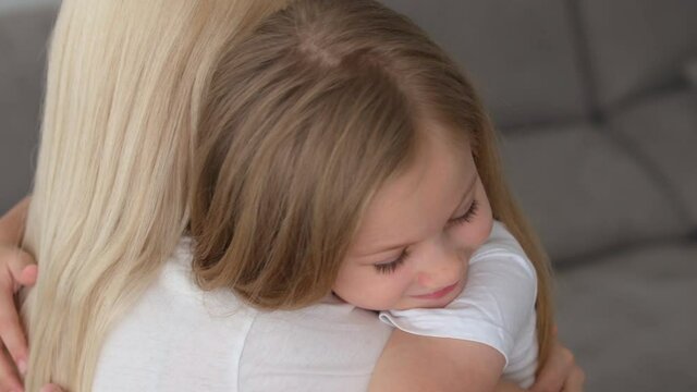 Happy affectionate family single mum and cute little child daughter embracing bonding laughing together, young mother foster parent hugging small kid girl cuddling enjoy tender moment of love at home