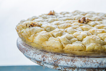 Close-up view of oriental dessert baklava on stand. Antique cake stand with syrupy baklava and walnuts on white background.