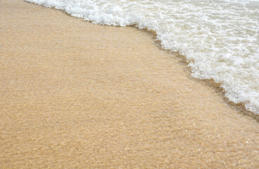 Natural freshness background of white clear sea wave foam on beach sand