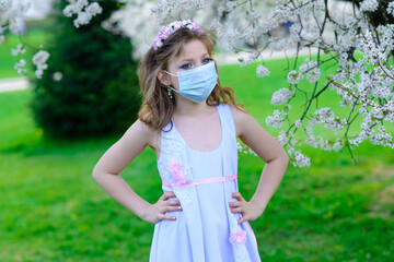 Lonely teenage girl wearing protection medicine mask against virus and allergy enjoying spring flower blossom in blooming garden