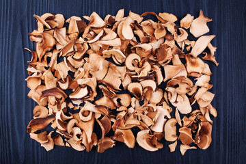 Obraz na płótnie Canvas Edible dried mushrooms pile black wooden background close up, dry boletus edulis heap dark wood backdrop, chopped brown cap boletus, sliced penny bun, cep pieces, porcino, porcini, cutted white fungus