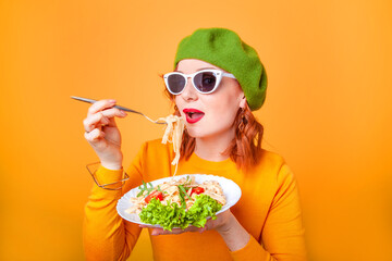 woman in green beret eats pasta on beige background in studio