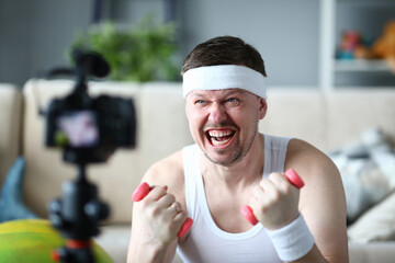 Close up of emotional sportsman that lifting dumbbells