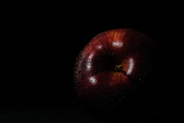 Close up fresh red Apple with water droplet isolated on black background – lowkey macro shoot