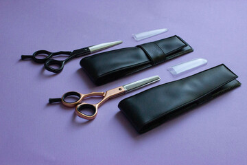 Hairdressing scissors. For cutting and milling. Black and rose gold. Next to the covers of leather and caps tips on the blade. Solid purple background. Base, banner, postcard.