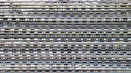 Close-up of a gray metal mesh as a security measure in front of a closed shopping center. Closed gates at the entrance to the store that impede the entry or destruction of places for criminals.