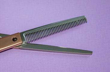 The blade of the Barber's milling scissors. In the clear. Solid purple background. Base, banner, postcard.