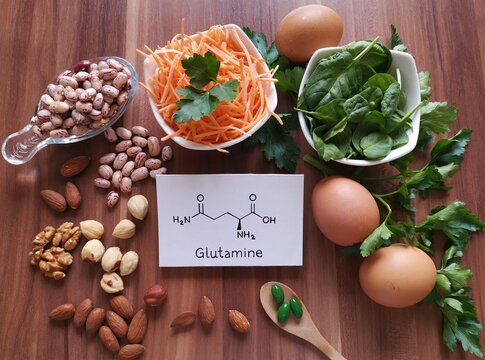 Food rich in glutamine with structural chemical formula of glutamine molecule. Food for training and exercise: spinach, egg, parsley, carrot, bean, almond, walnut, pills. Bodybuilding, sport nutrition