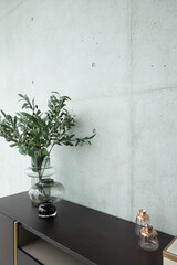 Stylish working corner artificial plant in glass vase on wood working table with concrete wall background /apartment interior /copyspace
