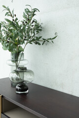 Stylish working corner artificial plant in glass vase on wood working table with concrete wall background in close up view /apartment interior /copyspace