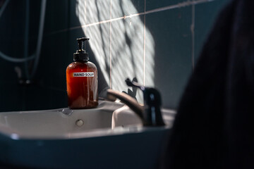 Liquid hand Soap bottle on the lavatory basin for wash hand in the bathroom that sun shine in the morning