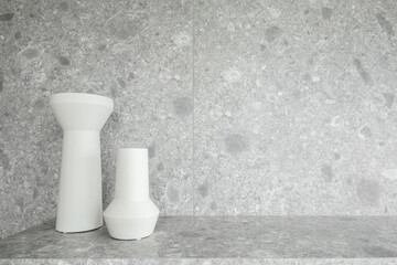 Bedroom working corner decorated with white ceramic vase and black glass vase on  gray marble top with  marble wall in the background /apartment interior /copyspace