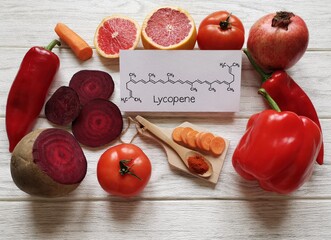 Foods rich in lycopene with structural chemical formula of lycopene molecule. Natural sources of lycopene: tomato, grapefruit, pomegranate, red bell pepper, beetroot, chili powder and carrot.