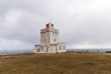 Fototapeta na wymiar Moody photo of a famous Dyrholaey light house in Iceland. Drama sky and windy weather.