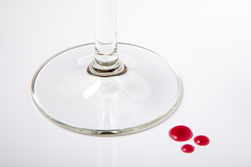 Base de copa de cristal de vino con tres gotas de vino sobre fondo blanco
