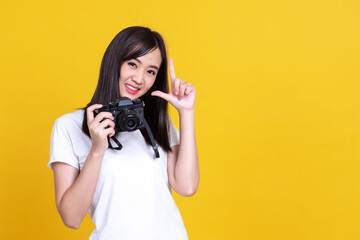 Fototapeta premium Portrait photo of Asian smiling pretty girl in white shirt taking photo on camera isolated over orrange background