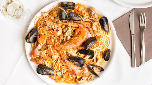Spaghetti with seafood.Spicy spaghetti with mussels, clams, calamari, shrimp, crab, in tomato sauce close-up on a plate.Famous mediterranean Italian seafood dish -spaghetti allo scoglio