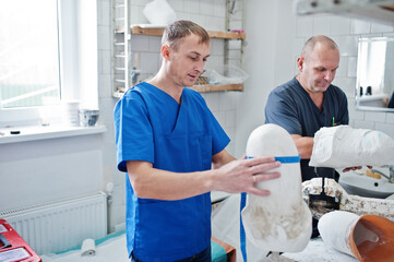 Fototapeta premium Two prosthetist man workers making prosthetic leg while working in laboratory.