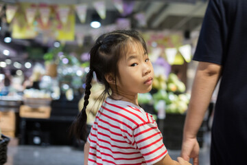 Beautiful young mom and her little daughter are walking in supermarket