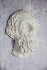the plaster head of an ancient Greek philosopher looks at the camera