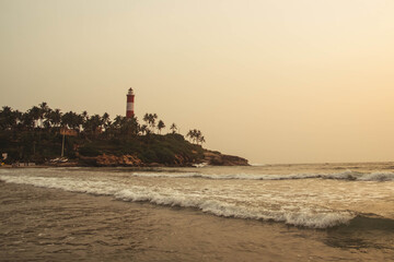 Obraz premium Lighthouse on the beach at morning dramatic sky in Kovalam, Kerala, India. Copy, empty space for text