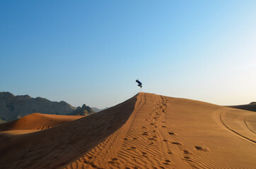 Boy takes giant leap off a sand dune in the Al Faya Desert near Dubai