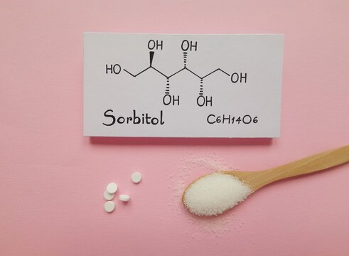 Structural chemical formula of sorbitol molecule with sorbitol tablets and sugar substitutes in wooden spoon. Sorbitol is an artificial sweetener and food additive, also used in modern cosmetics.