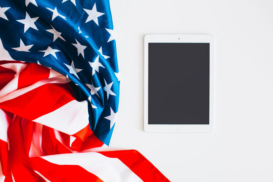 American flag and digital tablet on white table, shoot from above. Space for message, flat lay.