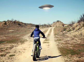 A boy riding a bicycle following a UFO. I want to believe. Photo with 3d rendering element - Powered by Adobe