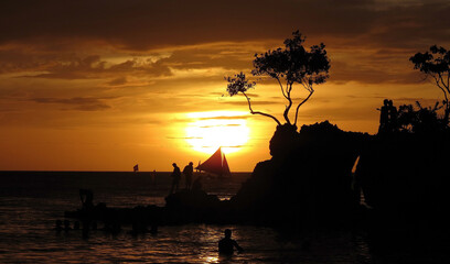 Yellow orange sunset on the sea. Small waves, beautiful sky, yellow sun and silhouettes of people. Thailand (Phuket) in the evening.