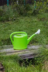 Green watering can stands on the ground for working in the garden and garden in the summer © Dancer01