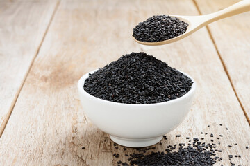Poppy seeds in a white cup and in a wooden spoon placed on an old wooden table